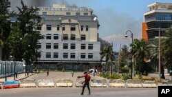 Foto Achiv: Yon mesye pase devan Pale Nasyonal la nan Potoprens, Ayiti, 2 Avril, 2024. 