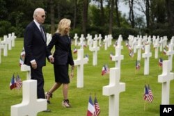 Prezidan Joe Biden ak premye dam Jill Biden mache nan simitye Ameriken Normandy a apre yon seremoni pou komemore 80e anivese D-Day, 6 Jyen 2024.