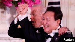 Tổng thống Hoa Kỳ Joe Biden (phía sau) và Tổng thống Hàn Quốc Yoon Suk Yeol bày tỏ cảm xúc hào hứng tại Quốc yến ở Nhà Trắng, trong chuyến thăm của ông Yoon Suk Yeol tới Hoa Kỳ vào ngày 26 tháng 4 năm 2023.