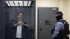 Wall Street Journal reporter Evan Gershkovich, who is in custody on espionage charges, makes a heart-shaped gesture inside an enclosure for defendants before a court hearing in Moscow, April 23, 2024.