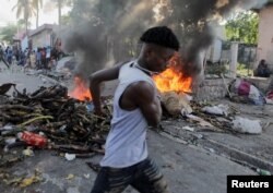 Yon gason kouri bo kote yon barikad kap boule pandan yon manifestasyon kont gouvenman an ak ogmantasyon pri petwol la nan Potoprens, Ayiti, 3 Oktob, 2022.