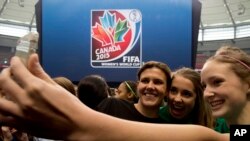 Cầu thủ Christine Sinclair của đội tuyển Canada chụp hình với người hâm mộ bên huy hiệu của World Cup Bóng đá nữ Canada 2015.