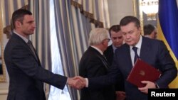 Tổng thống Ukraina Viktor Yanukovich bắt tay với nhà lãnh đạo đối lập Vitaly Klitschko (trái) sau khi ký kết thỏa thuận chấm dứt khủng hoảng