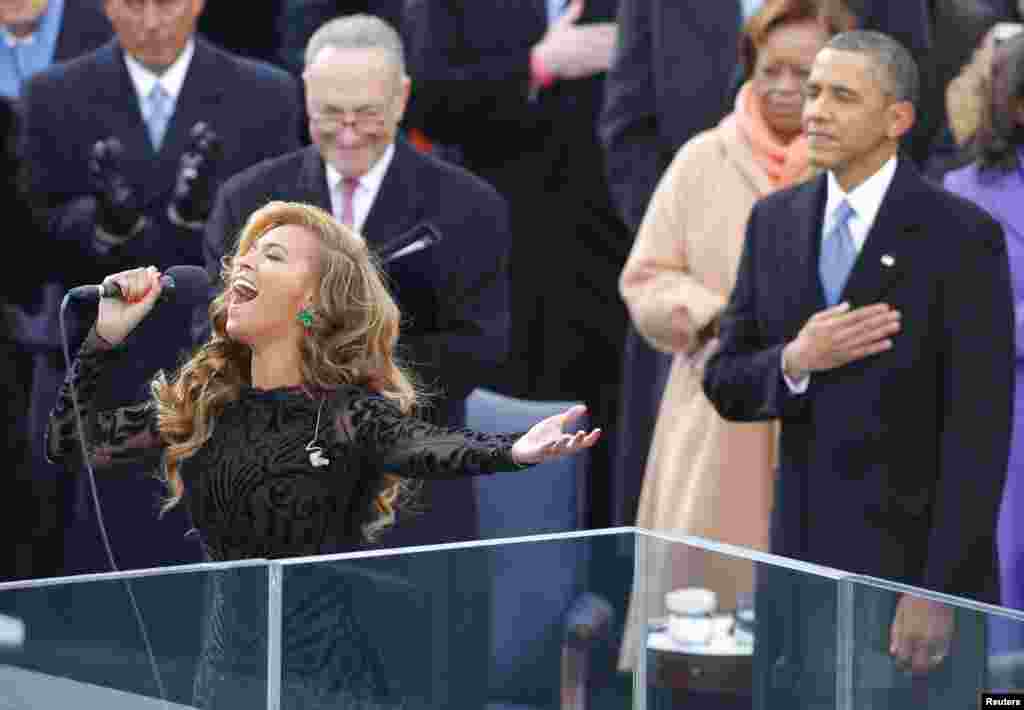 Tr&ecirc;n kh&aacute;n đ&agrave;i, ca sĩ Beyonce h&aacute;t quốc ca, ph&iacute;a sau l&agrave; Tổng thống Obama v&agrave; Thượng nghị sĩ Charles Schumer của New York (đeo k&iacute;nh) tại lễ nhậm chức nhiệm kỳ hai của Tổng thống Obama. (Reuters)