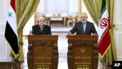 Ngoại trưởng Iran Mohammad Javad Zarif (phải) và Ngoại trưởng Syria Walid al-Moallem trong cuộc họp báo chung ở Tehran, 8/12/14