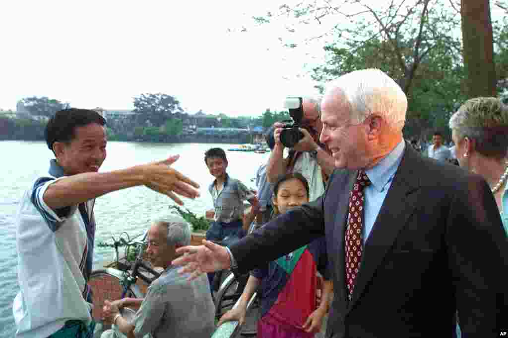 Thượng nghị sĩ John McCain bắt tay chào một người dân trên bờ hồ Trúc Bạch ở Hà Nội, ngày 26 tháng 4 năm 2000. &ldquo;Kiểm tra tình trạng bức tượng của tôi lúc nào cũng là điều tốt,&rdquo; ông nói với phóng viên của AP, nhắc tới tấm bia dựng tại hồ này kỉ niệm sự kiện ông bị bắn rơi vào năm 1967. &ldquo;Đó là bức tượng duy nhất mà tôi có,&rdquo; ông nói và cười tươi. Chuyến đi Việt Nam này của ông diễn ra không lâu sau khi ông rút khỏi cuộc đua giành đề cử tổng thống của Đảng Cộng hòa vào đầu tháng 3 sau những thất bại liên tiếp trước ứng cử viên đồng đảng George W. Bush.