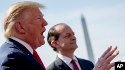 TT Trump và Bộ trưởng Lao động Alex Acosta (phải) đối mặt với truyền thông trên bãi cỏ phía Nam Tòa Bạch Ốc, ngày 12/7/2019. (AP Photo/Andrew Harnik)