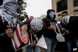 Người Palestine cầm áp phích có hình ảnh Tổng thống Mỹ Donald Trump trong cuộc biểu tình ở thành phố Ramallah ở Bờ Tây hôm 6/12 sau khi ông Trump tuyên bố kế hoạch công nhận Jerusalem là thủ đô của Israel.