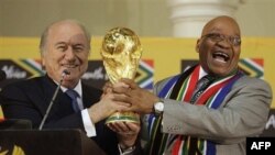 TT Nam Phi Jacob Zuma (phải) tươi cười trao lại chiếc cúp vàng cho Chủ tịch FIFA Joseph Blatter trong một cuộc họp báo về World Cup 2010 tại Nhà khách Tổng thống ở Pretoria, Nam Phi, Chủ nhật, ngày 6 tháng 6, 2010.