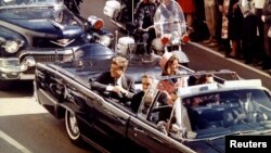 Tổng thống John Kennedy và Đệ nhất Phu nhân Jacqueline Kennedy trong 1 chiếc xe chở tổng thống mui trần, di chuyển giữa đoàn hộ tống vào khoảnh khắc trước khi ông bị ám sát, 22/11/1963.