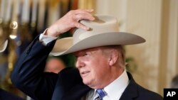 Tổng Thống Trump đội thử một chiếc mũ Stetson, sản phẩm của bang Texas, trong tuần "Made in America," quảng bá hàng hóa sản xuất tại mỗi bang của Hoa Kỳ tại Tòa Bạch Ốc, ngày 17/7/2017. (Ảnh AP/Alex Brandon)