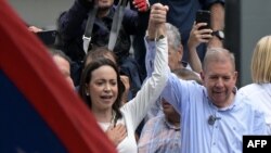 Venezuelan opposition leader Maria Corina Machado rises the hand of opposition presidential candidate Edmundo Gonzalez Urrutia during a rally in front of the United Nations headquarters in Caracas on July 30, 2024.