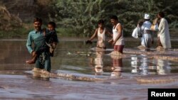 Nạn nhân lũ lụt lội qua 1 cánh đồng ngập nước sau trận mưa lớn ở Jhang, tỉnh Punjab, 11/9/2014.