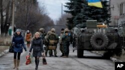 Cư dân làng Debaltseve, khu vực Donetsk, phía đông Ukraine đi ngang qua một nhóm các binh sĩ quân đội chính phủ Ukraine. 