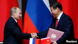 Tổng thống Nga Vladimir Putin, trái, và Chủ tịch Trung Quốc Tập Cận Bình bắt tay sau khi ký một thoả thuận tại cuộc gặp song phương tại Nhà khách Xijiao, Thượng Hải, ngày 20/5/2014.