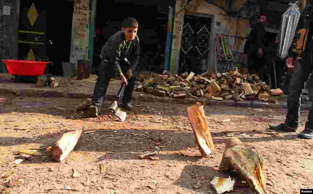 B&eacute; trai chặt củi để sưởi ấm tại th&agrave;nh phố Aleppo, Syria, ng&agrave;y 28/12/2012.