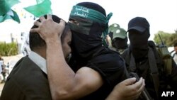 Chiến binh Hamas đeo mặt nạ ôm hôn tù nhân Palestine vừa được phóng thích, Mahawish al Qadi (trái), người đã tham gia vụ bắt cóc binh sĩ Israel Gilad Schalit tại Rafah