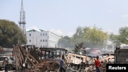 People walk past remains of vehicles after they were set on fire by gangs, in Port-au-Prince