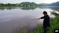 Nông dân Trung Quốc câu cá trên sông Ðồ Môn trong tỉnh Cát Lâm, phía đông bắc Trung Quốc, đối diện là đất nông nghiệp của Bắc Triều Tiên.