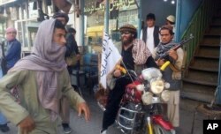 Chiến binh Taliban ngồi trên xe gắn cắm cờ Taliban trên đường phố ở thành phố Kunduz, ngày 29/9/2015.