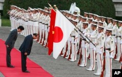 Thủ tướng Shinzo Abe (trái) và Thủ tướng Nguyễn Xuân Phúc cúi đầu trước quốc kỳ hai nước khi hai lãnh đạo có cuộc gặp tại Tokyo, Nhật Bản, vào ngày 6/6/2017.