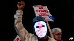 A Boeing worker wears a mask with a digital 'strike' sign as employees picket after union members voted overwhelmingly to reject a contract offer and go on strike Sept. 13, 2024, outside the company's factory in Renton, Wash. 