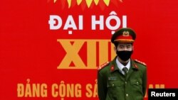 A police officer stands guard in front of a poster for the upcoming 13th national congress of the Communist Party of Vietnam on a street in Hanoi, Vietnam January 20, 2021. REUTERS/Kham