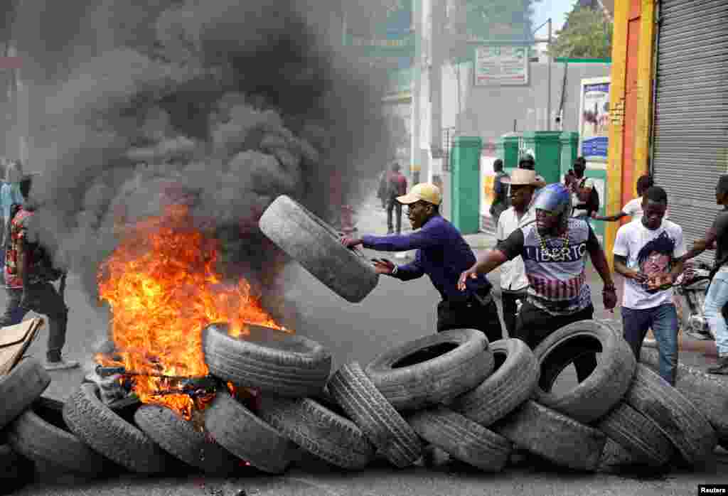 Manifestan yo aliyen yon pakèt kawotchou pou yo boule nan manifestasyon kont Prezidan Jovenel Moise.