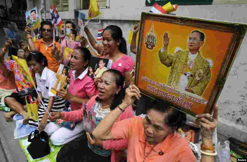 Đám đông ôm chân dung của Quốc vương Bhumibol Adulyadej và Hoàng hậu Sirikit chờ đợi bên ngoài bệnh viện.