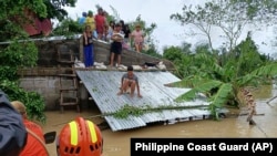 Người dân leo lên mái nhà để tránh lũ lụt và chờ được giải cứu ở Libon, tỉnh Albay, Philippines, vào ngày 23 tháng 10 năm 2024.