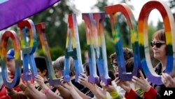 Cộng đồng LGBT cầm biểu ngữ tưởng nhớ các nạn nhân thiệt mạng trong vụ xả súng ở Orlando.