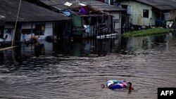 Trẻ em bám vào một chiếc phao bơi qua một con kênh nước dâng cao ở Bangkok, Thái Lan