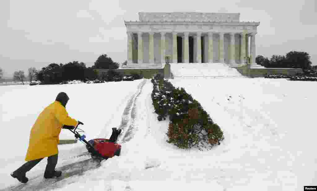 Nhân viên dùng máy thổi tuyết ra khỏi đường đi bộ đến Đài tưởng niệm Lincoln ở Washington, ngày 13/2/2014.