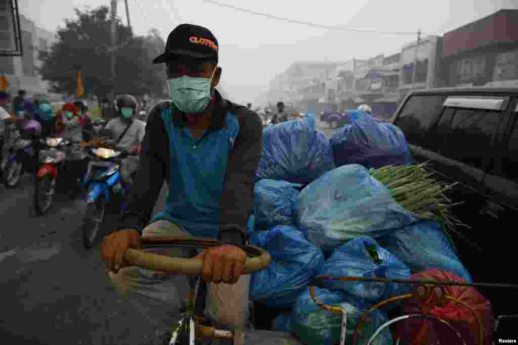 Một người bán hàng rong đeo mặt nạ để chống khói mù trên đường phố Dumai, Indonesia, ngày 21/6/2013.