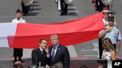 Tổng thống Pháp Emmanuel Macron và Tổng thống Hoa Kỳ Donald Trump đứng cạnh lá cờ lớn của Pháp sau cuộc diễu hành Ngày Bastille ở Paris, ngày 14/7/2017.