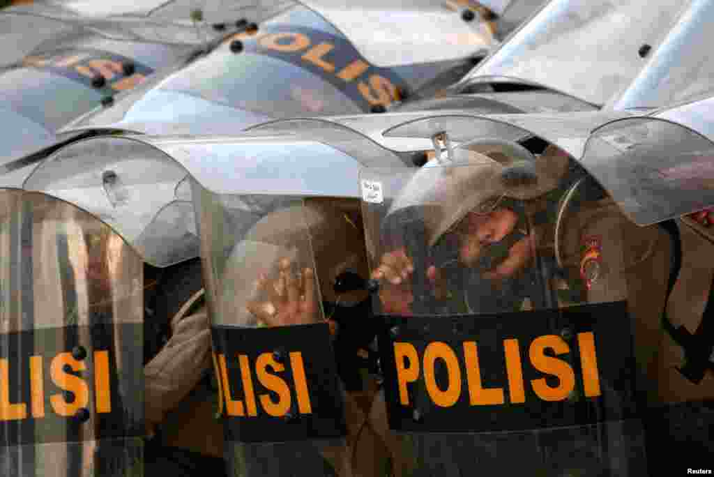 Riot police officers react as they guard during a riot following protests near Indonesian Parliament building in Jakarta, Indonesia.