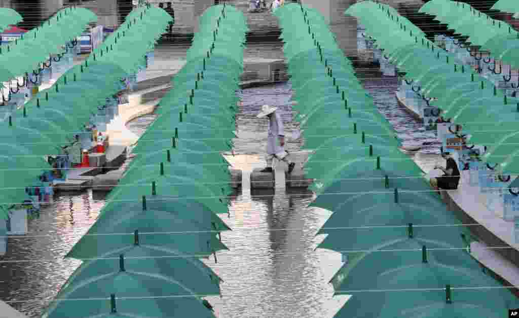 A Buddhist monk walks under the umbrellas on display over Cheonggye stream during a campaign to raise money to help underprivileged children in Seoul, South Korea.