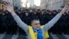 A man with a Ukrainian flag on his shoulders stands near a riot police line standing guard during an anti-war rally in Moscow, Sept. 21, 2014. 