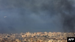 TOPSHOT - A Middle East Airlines commercial aircraft taking off from Beirut's international airport, flies amid smoke billowing above the Lebanese capital's southern suburbs, in the aftermath of overnight Israeli airstrikes, on September 28,2024.